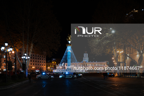 The main Christmas tree and New Year's illuminations are illuminated on Rustaveli Avenue as anti-government demonstrators gather outside the...