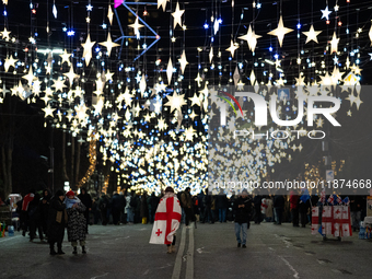 The main Christmas tree and New Year's illuminations are illuminated on Rustaveli Avenue as anti-government demonstrators gather outside the...