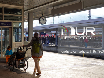 A family prepares to board their train at Garmisch-Partenkirchen station in the Bavarian Alps, Germany, on December 13, 2024. The mother pus...