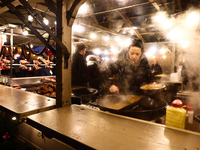 A person prepares food at the Christmas fair at Main Square in Krakow, Poland on December 16, 2024. (