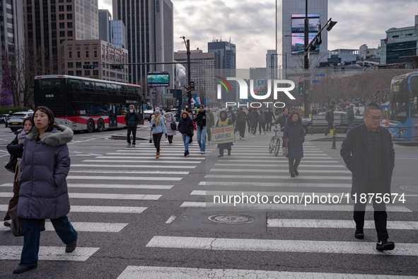 Citizens cross a pedestrian walkway at Gwanghwamun Square in Seoul, South Korea, on December 17, 2024. The city returns to calm following th...