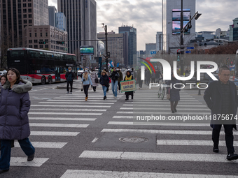 Citizens cross a pedestrian walkway at Gwanghwamun Square in Seoul, South Korea, on December 17, 2024. The city returns to calm following th...