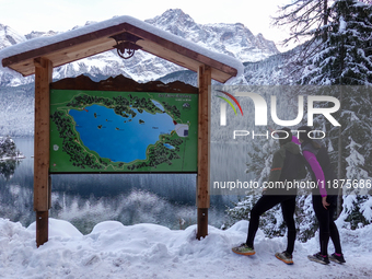 Visitors consult a trail map during a winter hike at Lake Eibsee in Grainau, Bavaria, Germany, on December 13, 2024. Two hikers stand in fro...