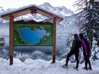 Visitors consult a trail map during a winter hike at Lake Eibsee in Grainau, Bavaria, Germany, on December 13, 2024. Two hikers stand in fro...