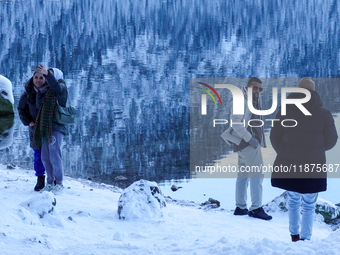 A group of people spends a winter day at Lake Eibsee, located 9 km southwest of Garmisch-Partenkirchen, Grainau, Bavaria, Germany, on Decemb...