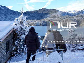 A group of people stands together on a winter day at Lake Eibsee, located 9 km southwest of Garmisch-Partenkirchen, Grainau, Bavaria, German...