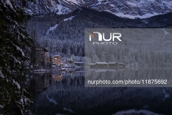 A snowy winter landscape with calm lake reflections appears at Lake Eibsee in Grainau, Bavaria, Germany, on December 13, 2024. A serene twil...