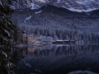 A snowy winter landscape with calm lake reflections appears at Lake Eibsee in Grainau, Bavaria, Germany, on December 13, 2024. A serene twil...