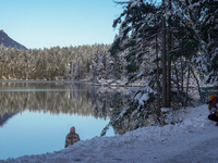 A photographer captures the reflection of snow-covered trees at Lake Eibsee in Grainau, Bavaria, Germany, on December 13, 2024. This winter...