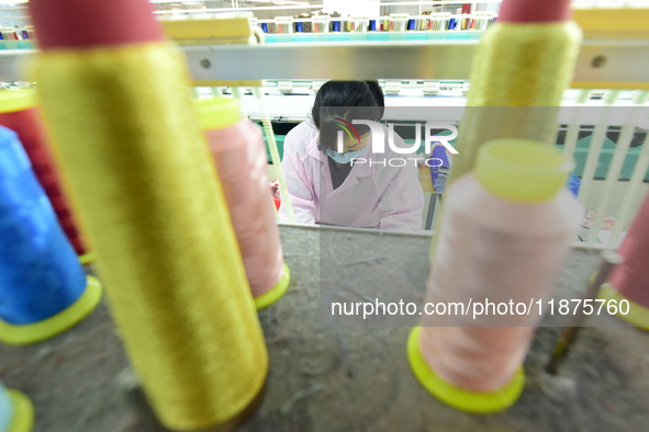 A female worker produces embroidery products for export at a workshop in Lianyungang, China, on December 17, 2024. 