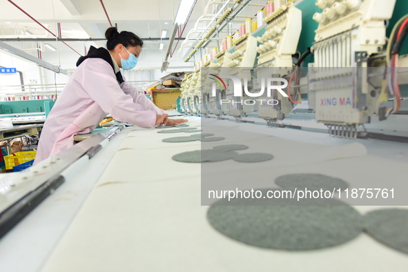 A female worker produces embroidery products for export at a workshop in Lianyungang, China, on December 17, 2024. 