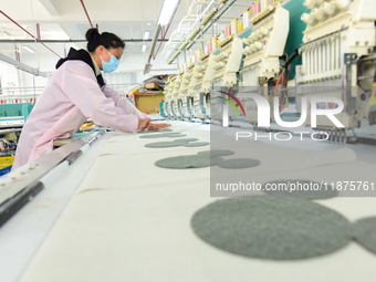 A female worker produces embroidery products for export at a workshop in Lianyungang, China, on December 17, 2024. (