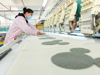 A female worker produces embroidery products for export at a workshop in Lianyungang, China, on December 17, 2024. (