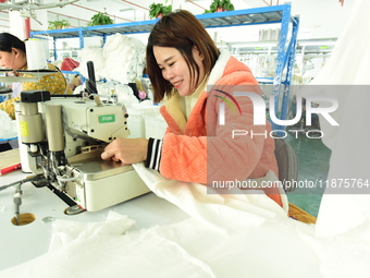 A female worker produces garments for export at a workshop in Lianyungang, China, on December 17, 2024. (