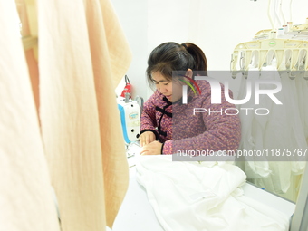 A female worker produces garments for export at a workshop in Lianyungang, China, on December 17, 2024. (