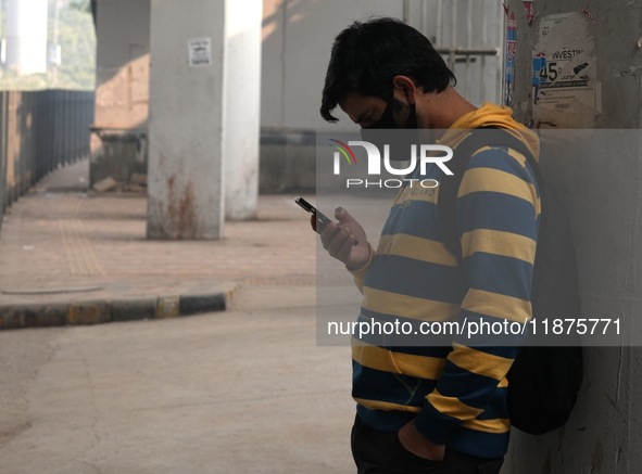 A young man wearing a face mask looks at his phone as the air quality index slips to the 'severe' category in New Delhi, India, on December...