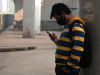 A young man wearing a face mask looks at his phone as the air quality index slips to the 'severe' category in New Delhi, India, on December...