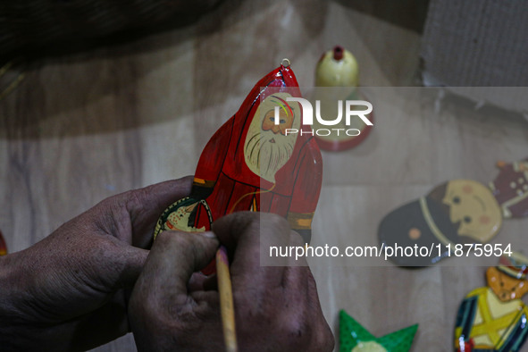 Muzaffar Hussain Dar, a Kashmiri artisan, paints Christmas gift items at the workshop before sending them to the market ahead of Christmas c...