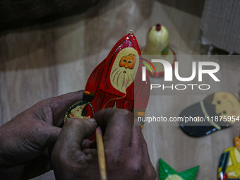 Muzaffar Hussain Dar, a Kashmiri artisan, paints Christmas gift items at the workshop before sending them to the market ahead of Christmas c...