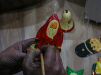 Muzaffar Hussain Dar, a Kashmiri artisan, paints Christmas gift items at the workshop before sending them to the market ahead of Christmas c...