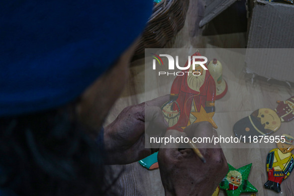 Muzaffar Hussain Dar, a Kashmiri artisan, paints Christmas gift items at the workshop before sending them to the market ahead of Christmas c...