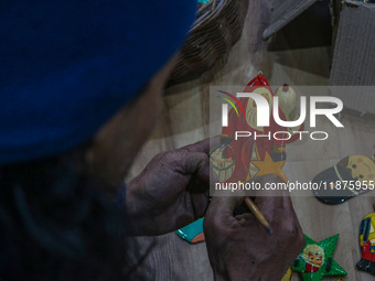 Muzaffar Hussain Dar, a Kashmiri artisan, paints Christmas gift items at the workshop before sending them to the market ahead of Christmas c...