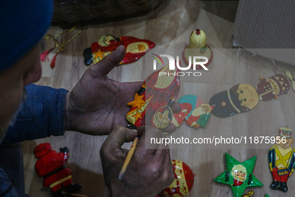 Muzaffar Hussain Dar, a Kashmiri artisan, paints Christmas gift items at the workshop before sending them to the market ahead of Christmas c...