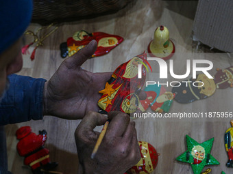 Muzaffar Hussain Dar, a Kashmiri artisan, paints Christmas gift items at the workshop before sending them to the market ahead of Christmas c...