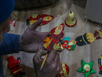 Muzaffar Hussain Dar, a Kashmiri artisan, paints Christmas gift items at the workshop before sending them to the market ahead of Christmas c...