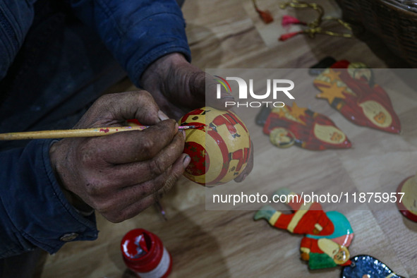 Muzaffar Hussain Dar, a Kashmiri artisan, paints Christmas gift items at the workshop before sending them to the market ahead of Christmas c...