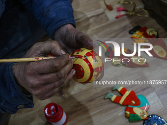 Muzaffar Hussain Dar, a Kashmiri artisan, paints Christmas gift items at the workshop before sending them to the market ahead of Christmas c...