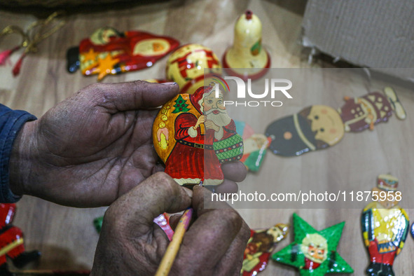 Muzaffar Hussain Dar, a Kashmiri artisan, paints Christmas gift items at the workshop before sending them to the market ahead of Christmas c...