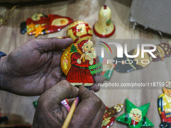 Muzaffar Hussain Dar, a Kashmiri artisan, paints Christmas gift items at the workshop before sending them to the market ahead of Christmas c...