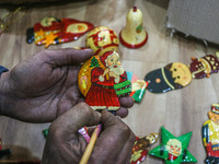 Muzaffar Hussain Dar, a Kashmiri artisan, paints Christmas gift items at the workshop before sending them to the market ahead of Christmas c...