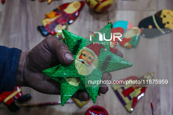 Muzaffar Hussain Dar, a Kashmiri artisan, paints Christmas gift items at the workshop before sending them to the market ahead of Christmas c...