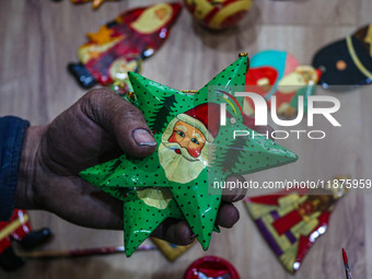 Muzaffar Hussain Dar, a Kashmiri artisan, paints Christmas gift items at the workshop before sending them to the market ahead of Christmas c...