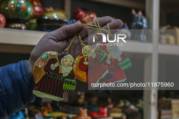 Muzaffar Hussain Dar, a Kashmiri artisan, holds a Santa Claus made of papier-mache at the workshop before sending it to the market ahead of...