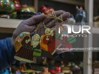 Muzaffar Hussain Dar, a Kashmiri artisan, holds a Santa Claus made of papier-mache at the workshop before sending it to the market ahead of...