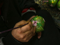 Showkat Haji, a Kashmiri artisan, paints Christmas gift items at the workshop before sending them to the market ahead of Christmas celebrati...