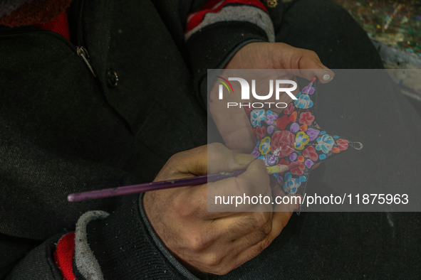 Showkat Haji, a Kashmiri artisan, paints Christmas gift items at the workshop before sending them to the market ahead of Christmas celebrati...