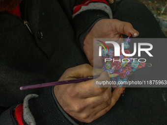 Showkat Haji, a Kashmiri artisan, paints Christmas gift items at the workshop before sending them to the market ahead of Christmas celebrati...