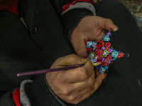 Showkat Haji, a Kashmiri artisan, paints Christmas gift items at the workshop before sending them to the market ahead of Christmas celebrati...