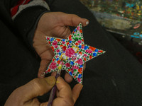 Showkat Haji, a Kashmiri artisan, paints Christmas gift items at the workshop before sending them to the market ahead of Christmas celebrati...