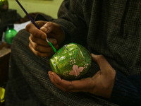 Fida Hussain Parray, a Kashmiri artisan, paints Christmas gift items at the workshop before sending them to the market ahead of Christmas ce...