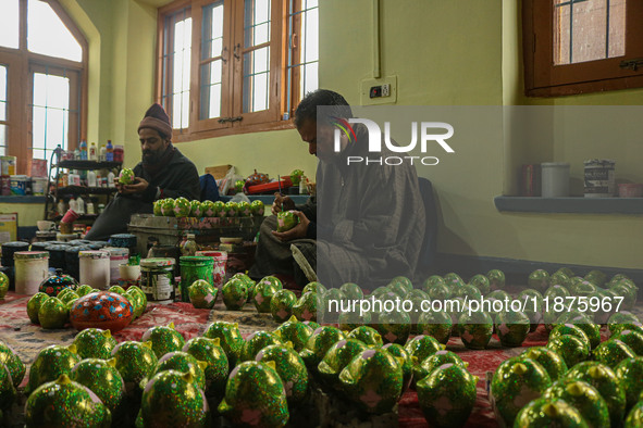 Showkat Haji (left) and Fida Hussain Parray (right), Kashmiri artisans, paint Christmas gift items at the workshop before sending them to th...