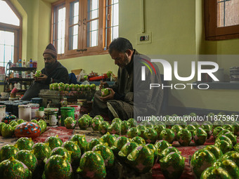 Showkat Haji (left) and Fida Hussain Parray (right), Kashmiri artisans, paint Christmas gift items at the workshop before sending them to th...