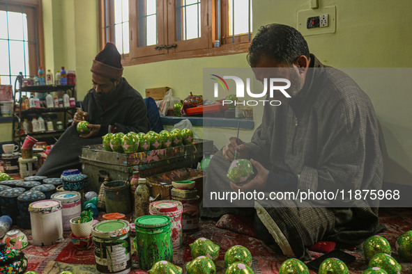 Showkat Haji (left) and Fida Hussain Parray (right), Kashmiri artisans, paint Christmas gift items at the workshop before sending them to th...