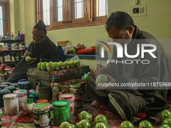 Showkat Haji (left) and Fida Hussain Parray (right), Kashmiri artisans, paint Christmas gift items at the workshop before sending them to th...