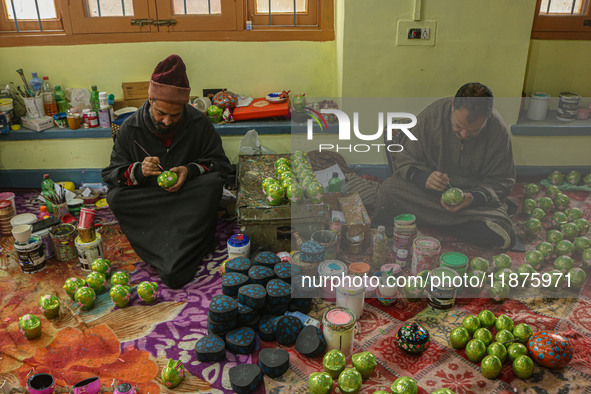 Showkat Haji (left) and Fida Hussain Parray (right), Kashmiri artisans, paint Christmas gift items at the workshop before sending them to th...