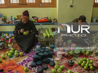 Showkat Haji (left) and Fida Hussain Parray (right), Kashmiri artisans, paint Christmas gift items at the workshop before sending them to th...